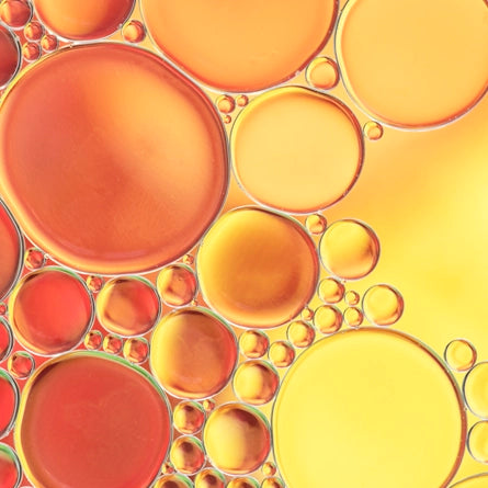 Close-up of oil and water bubbles in a yellow and orange color scheme.
