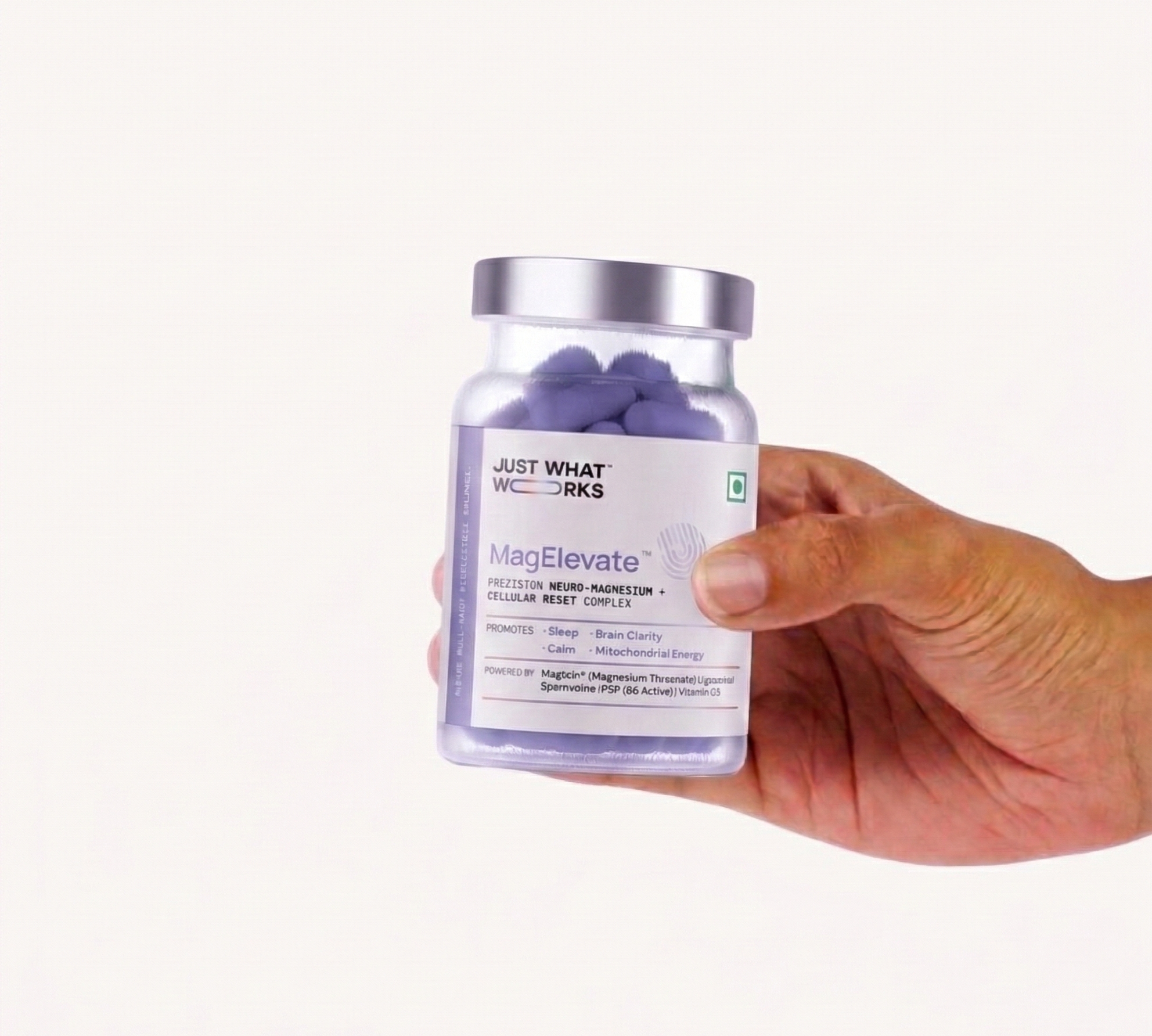Hand holding a jar of 'Just What Works' MagElevate supplement on a white background