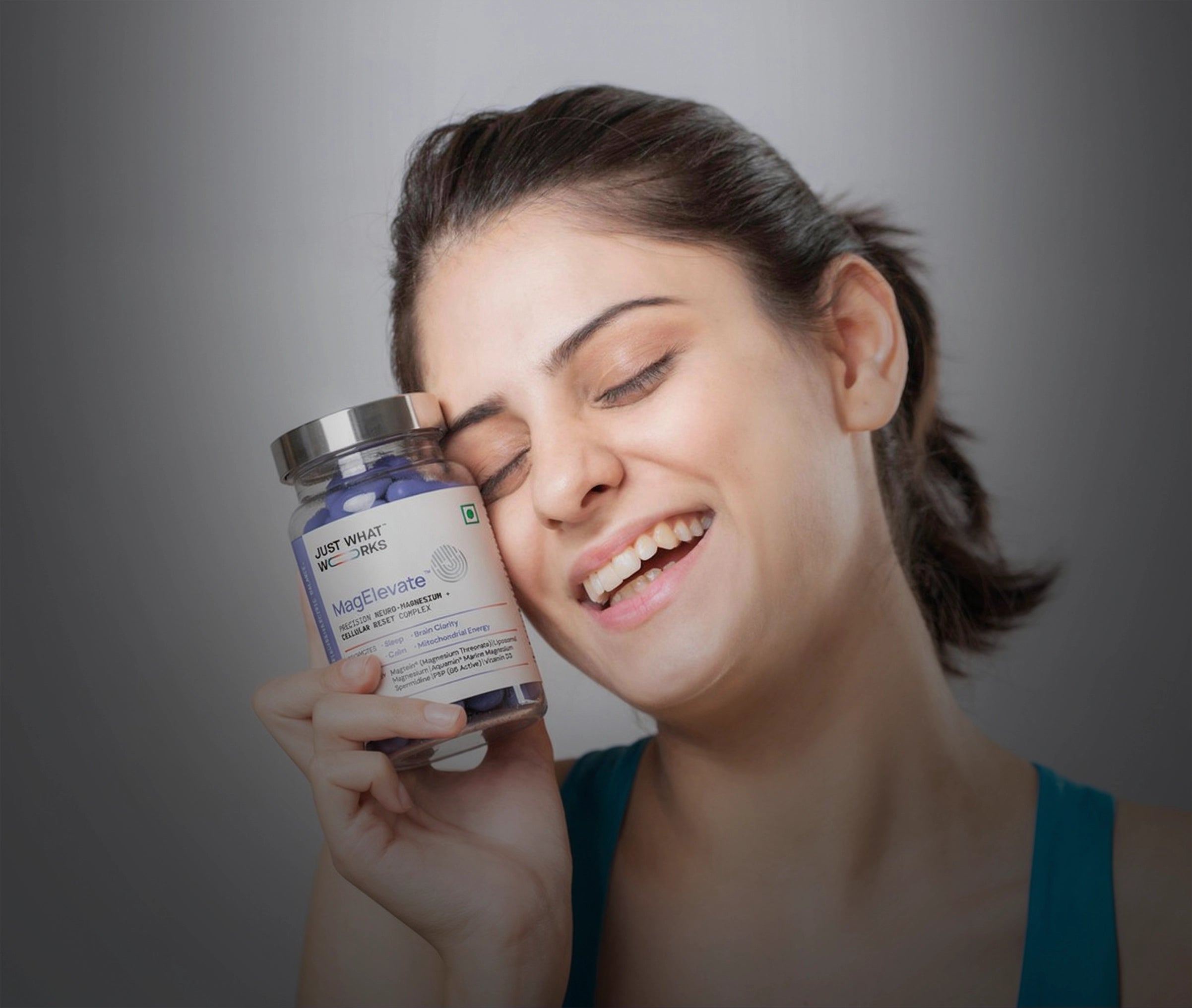 Woman holding a bottle of Just Naturals L-Glutamine supplement against a gray background