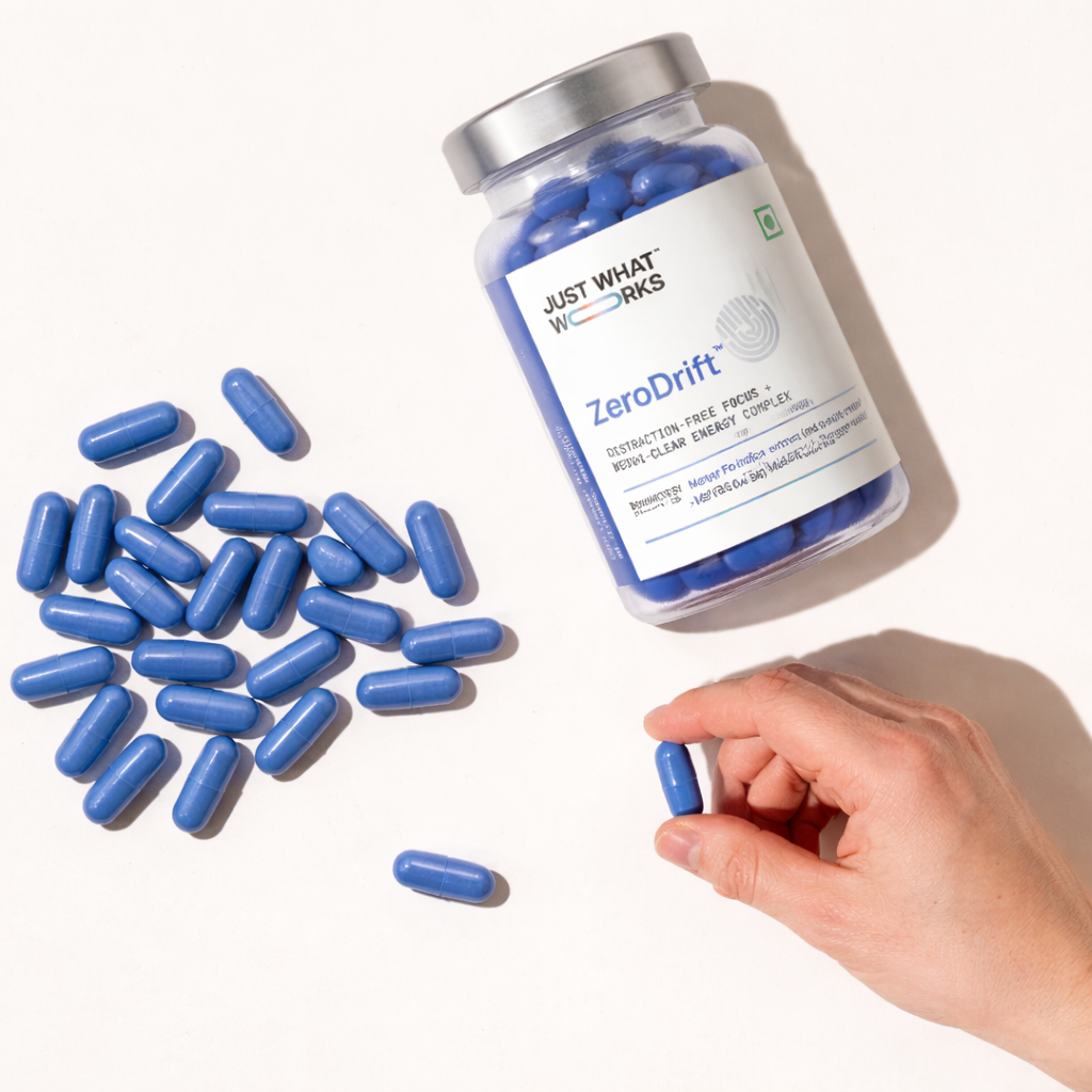 Bottle of Just What Works ZeroDrift supplement with blue capsules and a hand holding a capsule.